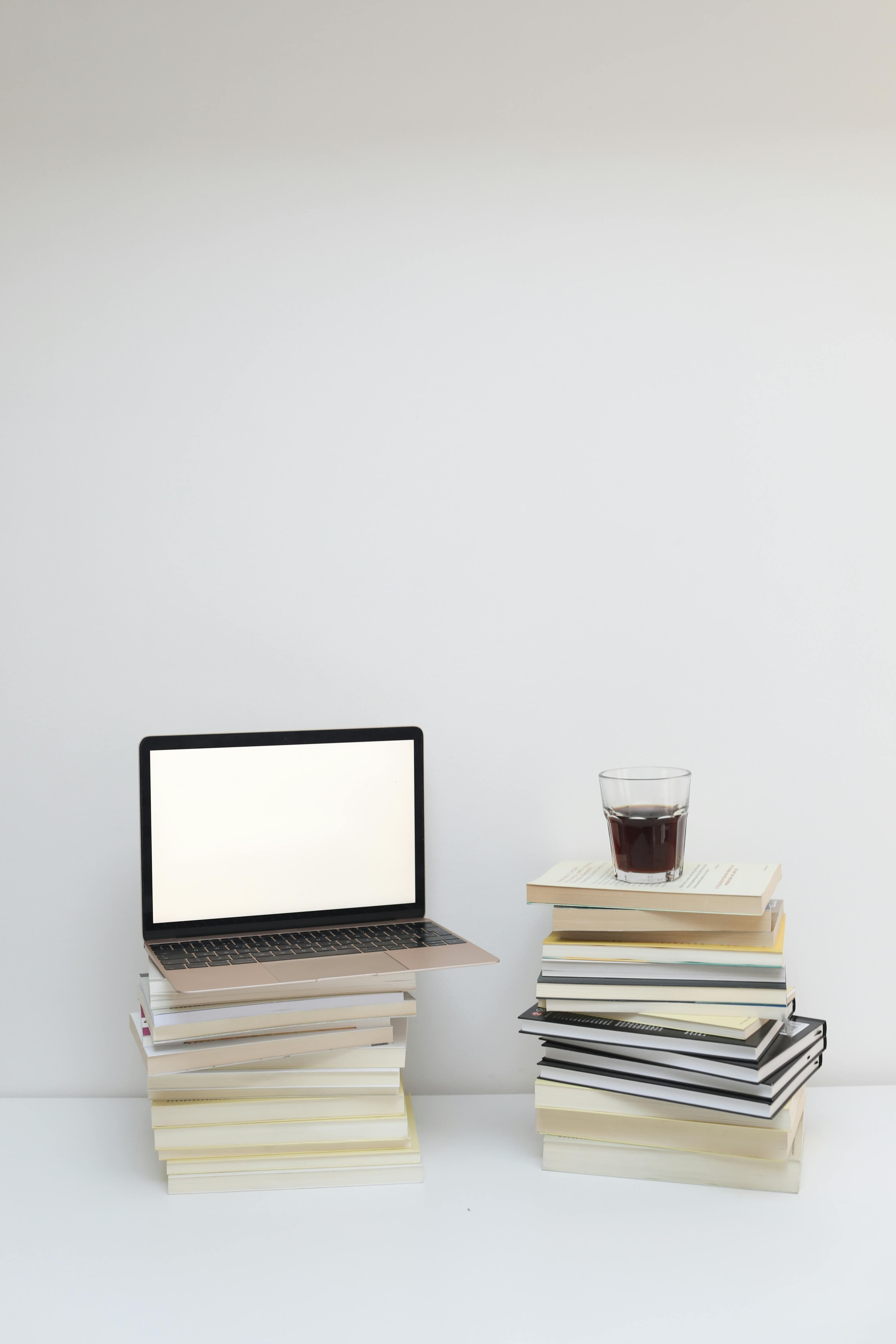 An author writing with a laptop and a pile of books